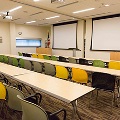 classroom setting with chairs, tables in a row facing two projection screens