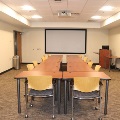Conference room with wooden tables, chairs, and a large projection screen.