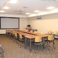 Conference room with wooden tables, chairs, and a large projection screen.