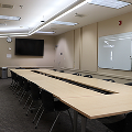 Square of tables lined with chairs white board on one wall, monitor on back wall