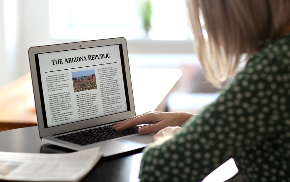 News image person using laptop with AZ Republic newspaper on screen