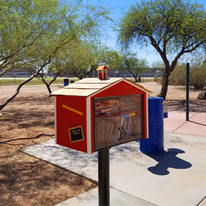 small box on pole painted to look like a small red schoolhouse with books inside