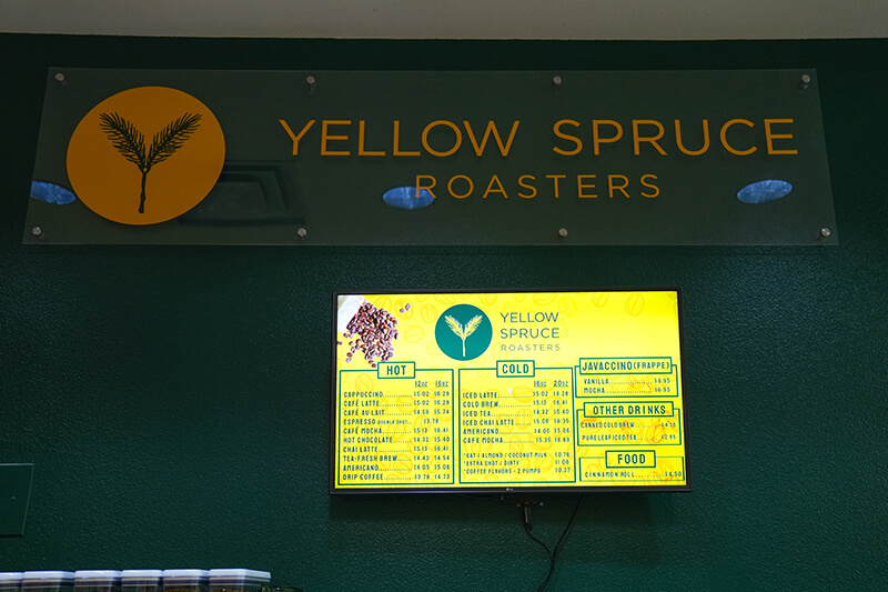 Yellow Spruce Roasters Menu green wall with Yellow Spruce logo and menu board posted